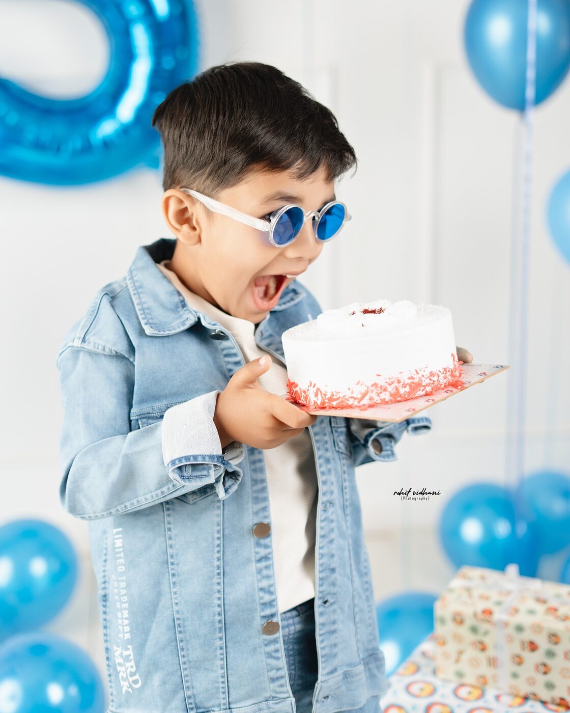 Kids birthday photoshoot, boy in leather jacket with black balloons